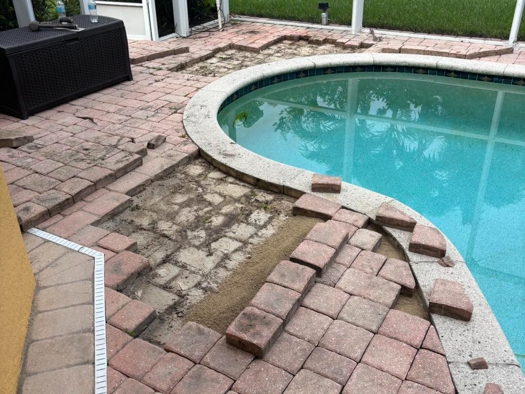 Removed pavers and exposed ground following the curved edge of a swimming pool