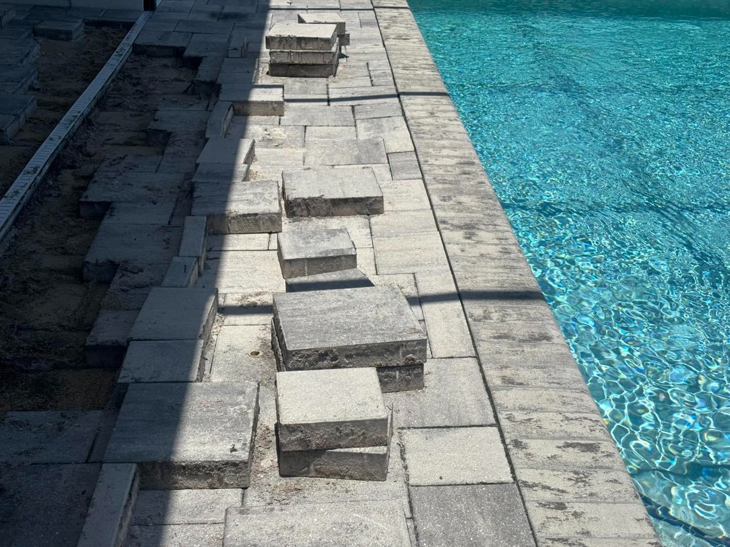 Rows of lifted rectangular pavers along a straight swimming pool edge