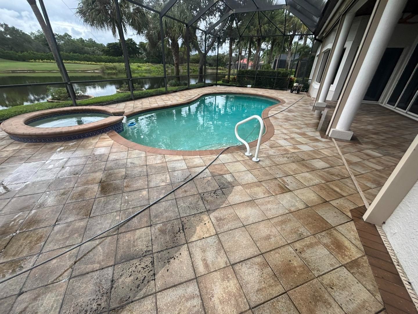 Screened swimming pool and circular spa surrounded by large square deck tiles