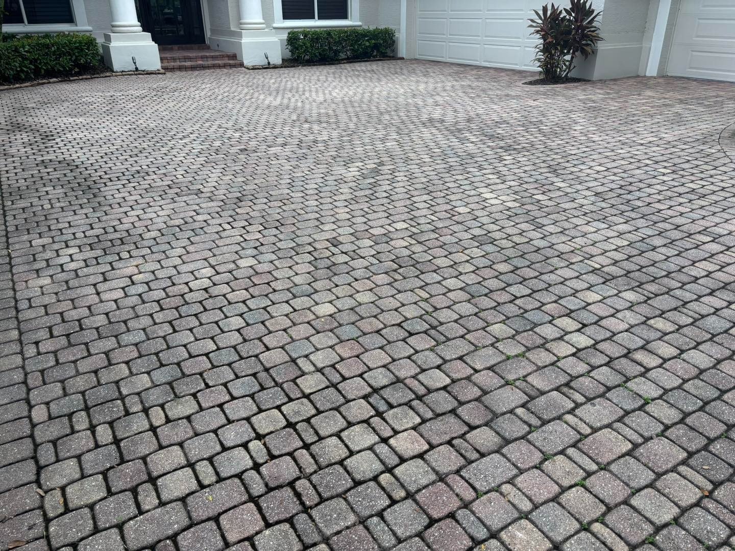 Small gray rectangular driveway pavers extending toward a house and garage
