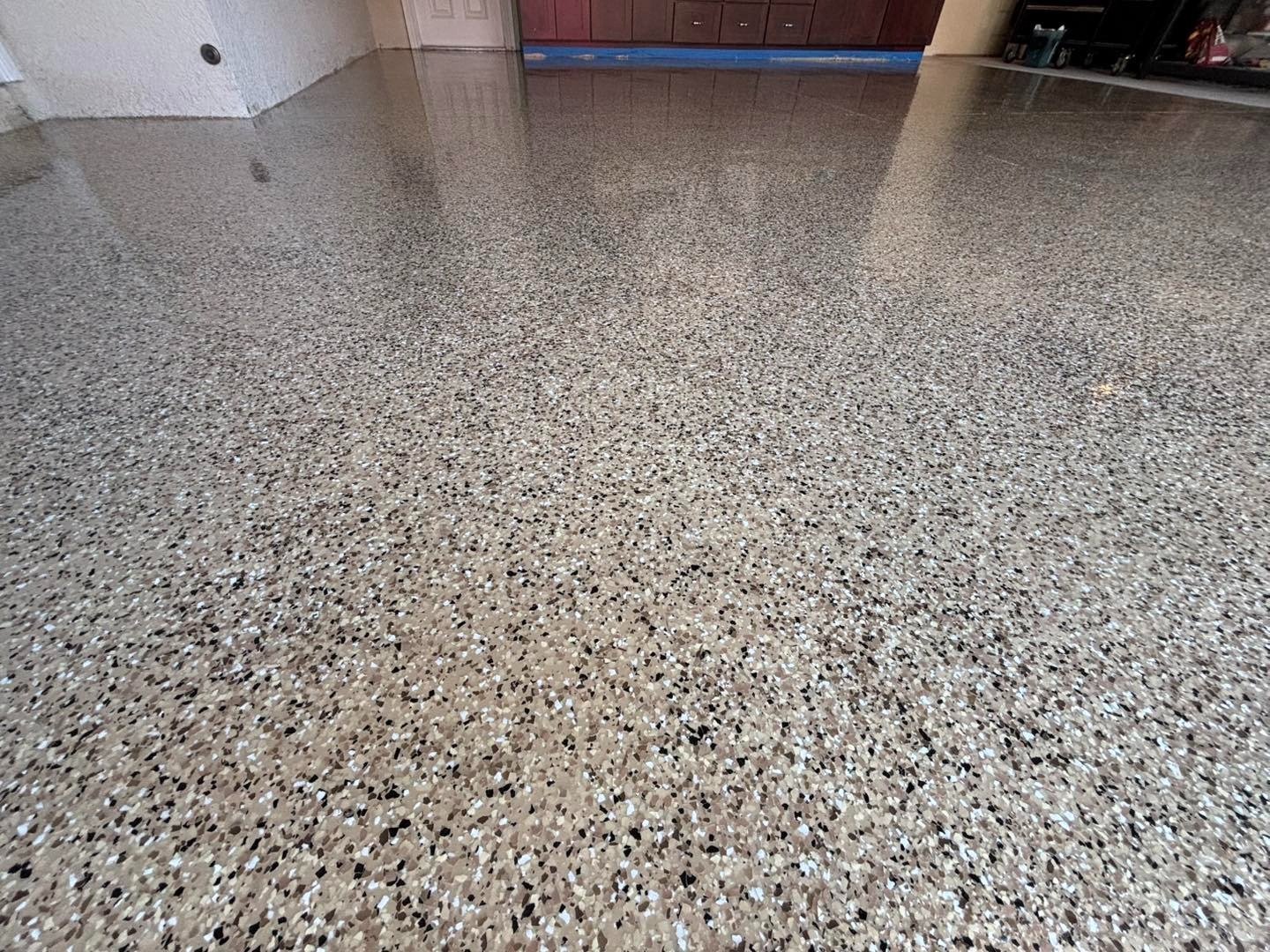 Speckled gray garage floor beneath wooden storage cabinets