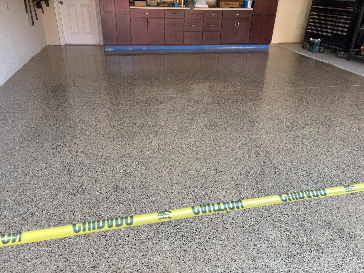 Speckled gray garage floor behind yellow caution tape at entrance