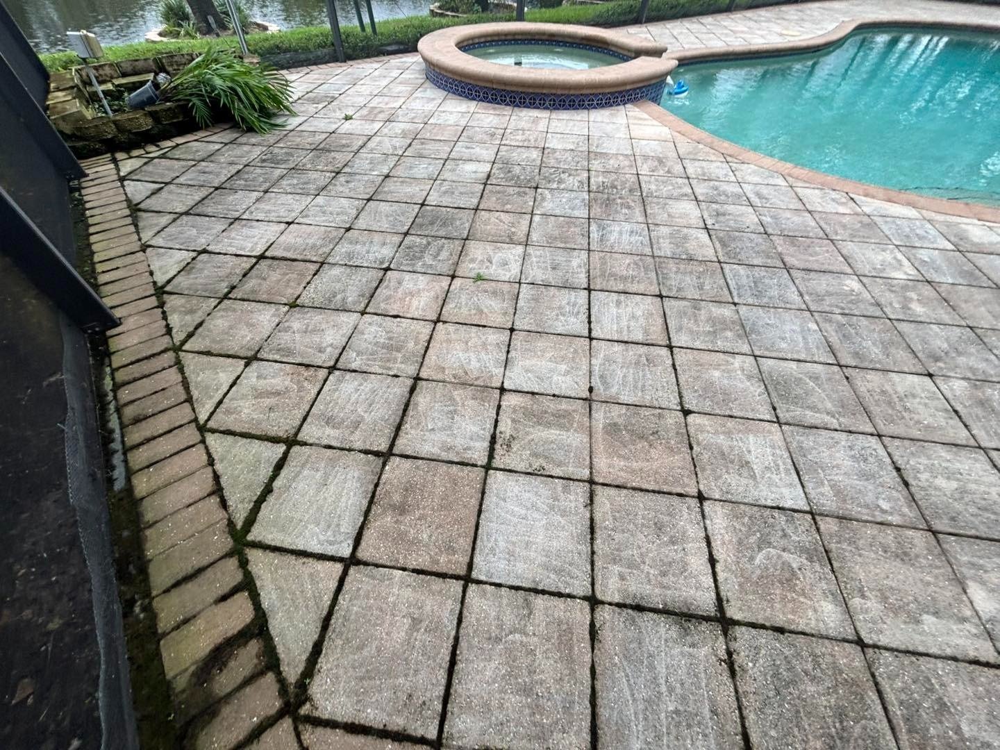 Square pool deck tiles with dark joints beside a raised circular spa