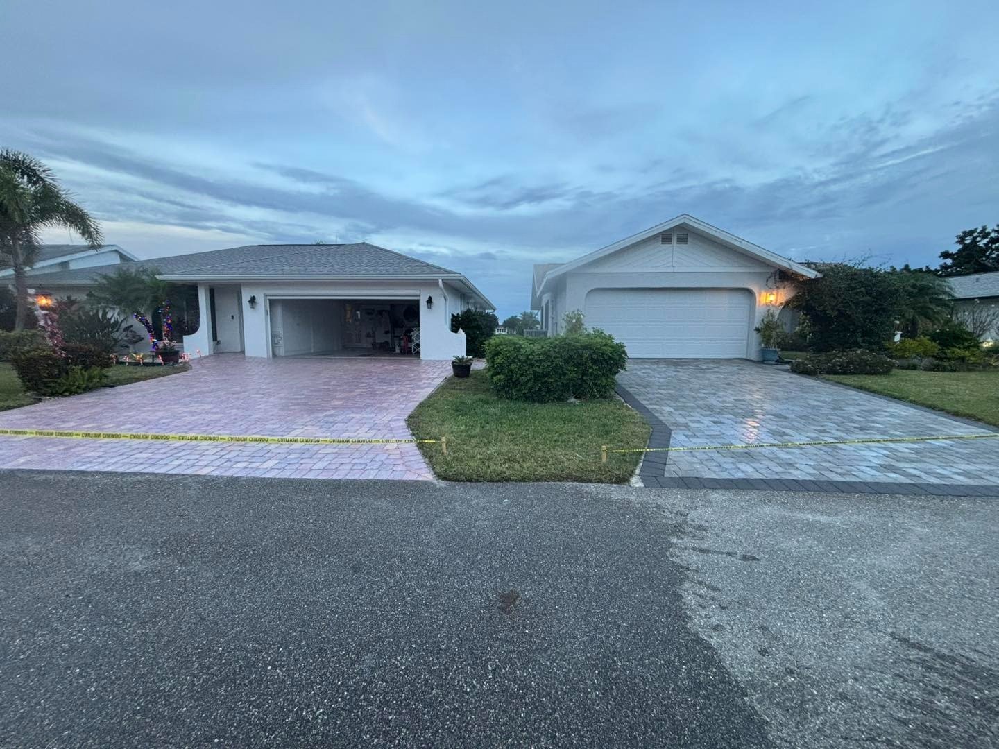Street view of neighboring paver driveways separated by a lawn