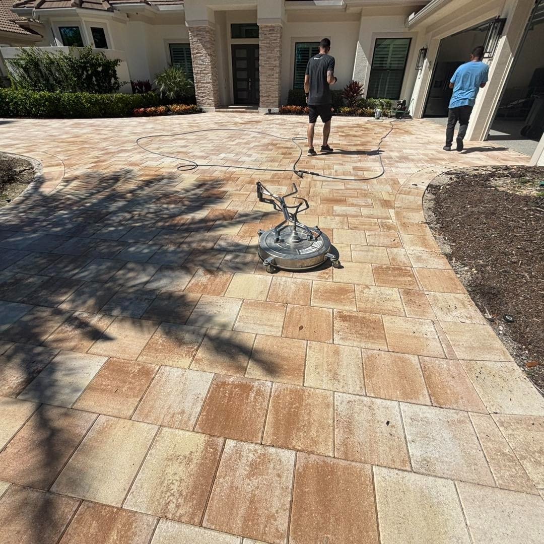 Surface cleaning equipment on a multicolored paver driveway outside a house