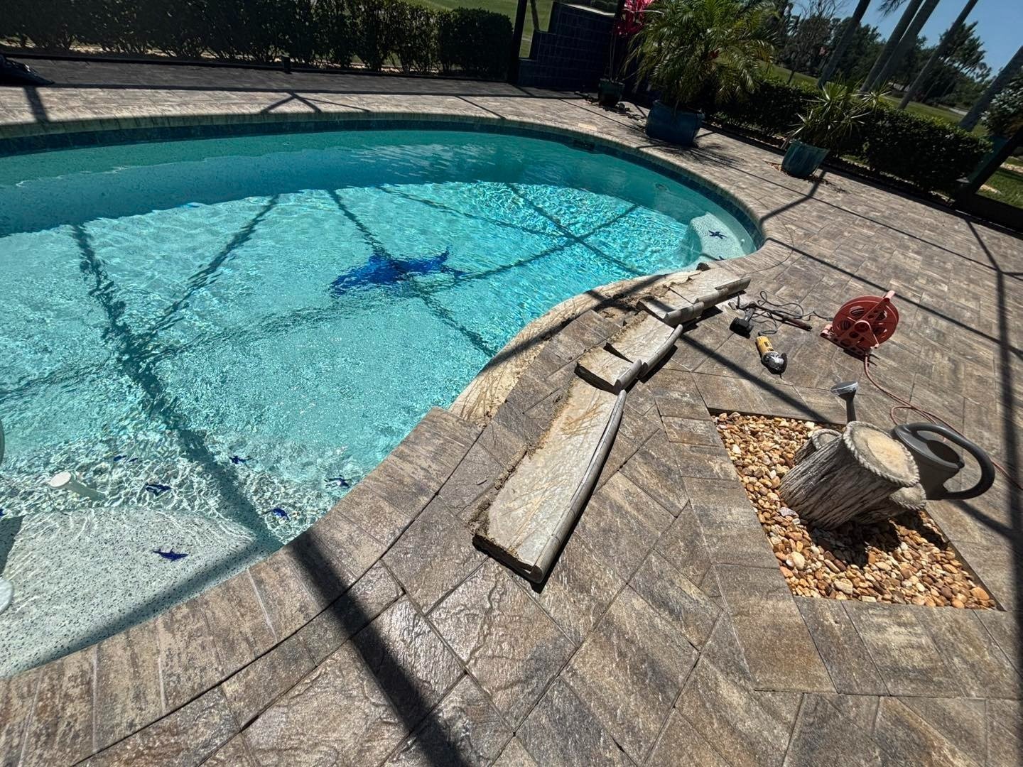 Swimming pool with removed coping pieces and tools on the deck