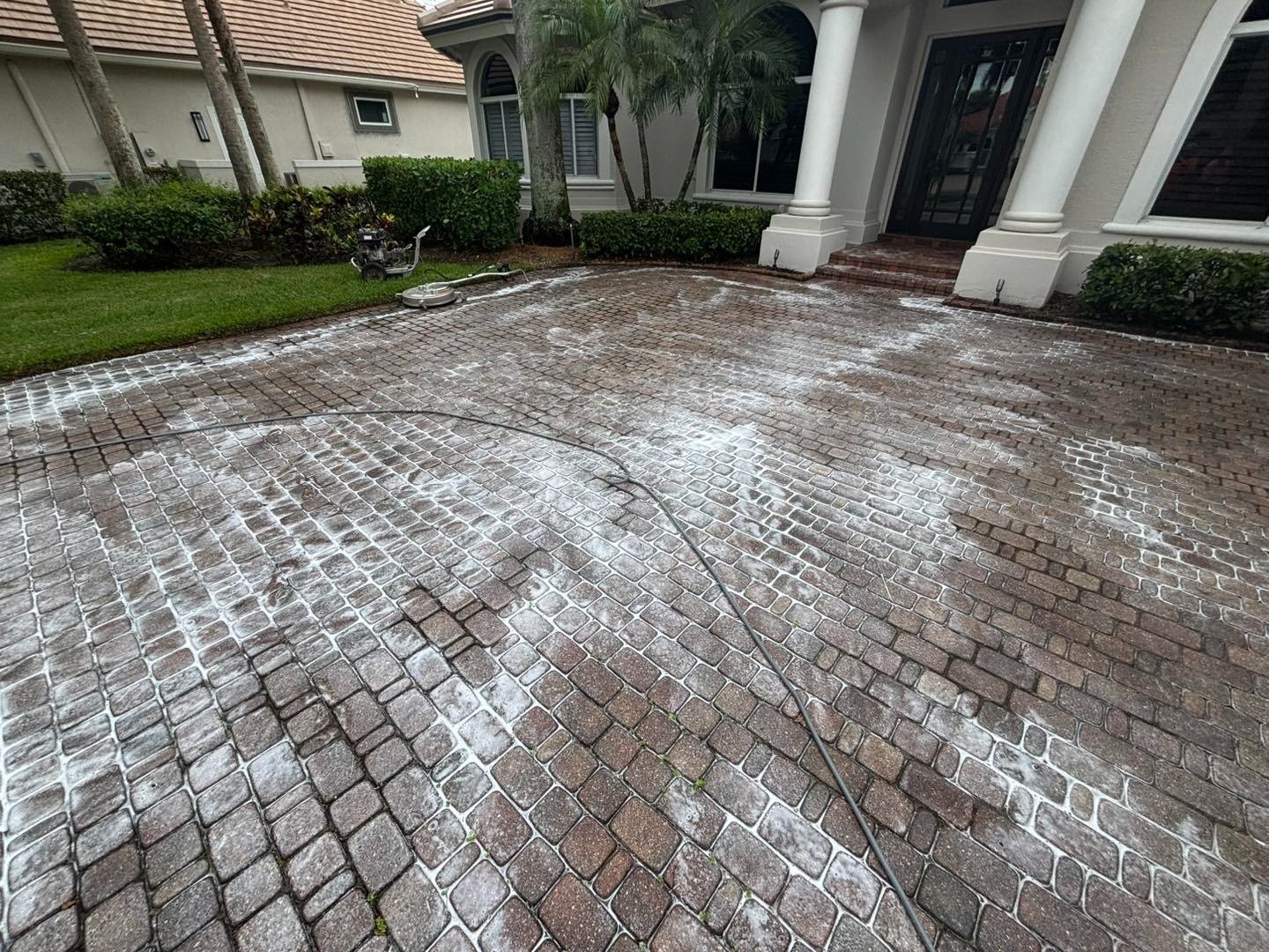 White foam spread across a small rectangular paver driveway outside a house