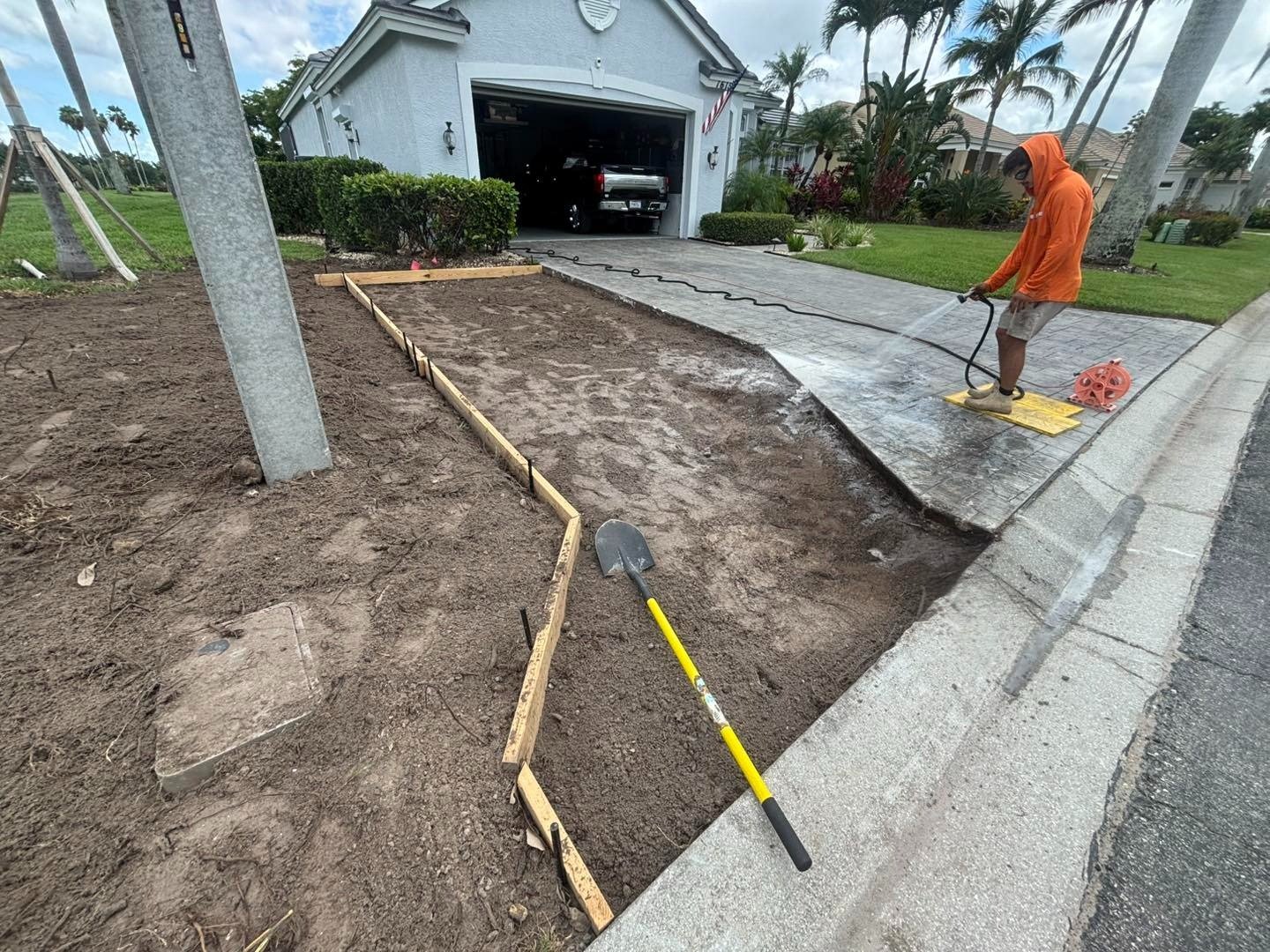 Worker beside driveway form boards bordering an area of exposed soil