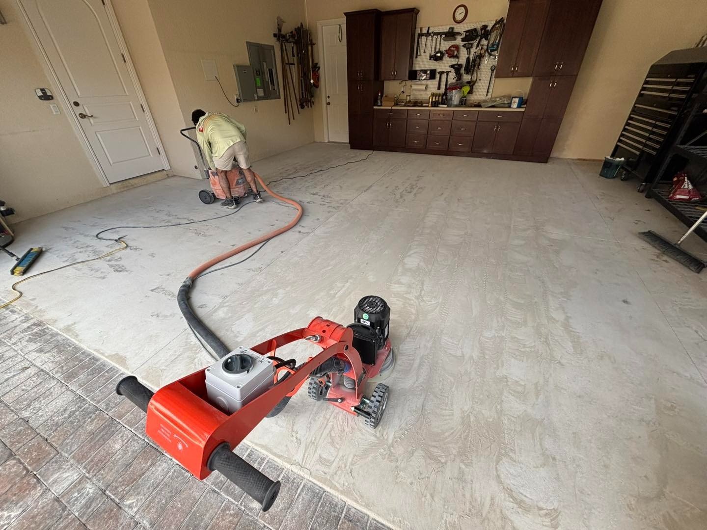 Worker using floor preparation equipment inside a residential garage