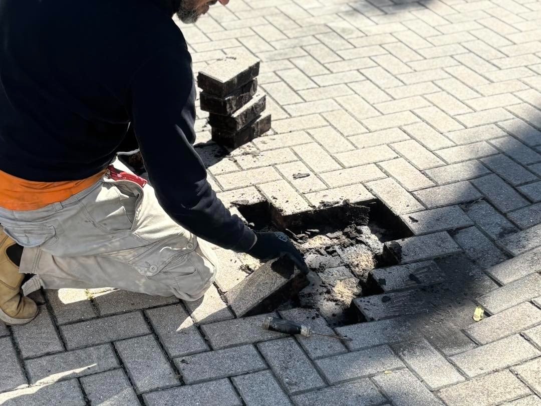 Worker lifting pavers from a small section of driveway