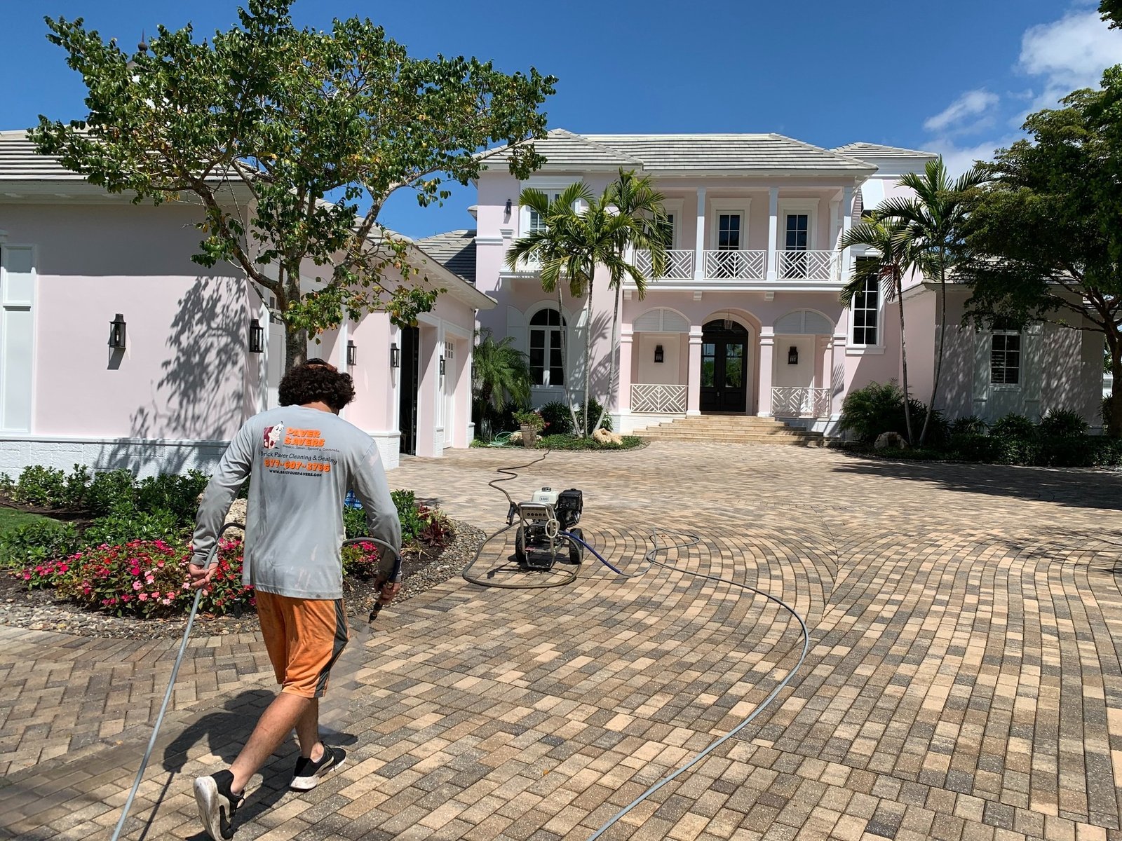 Worker walking across a paver driveway toward cleaning equipment