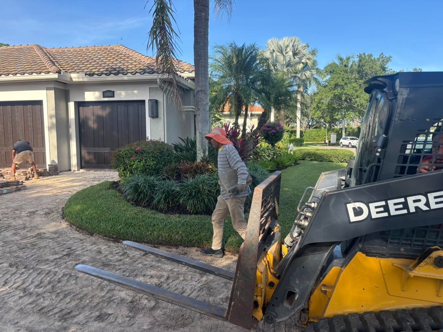 Worker beside a skid steer on a residential driveway