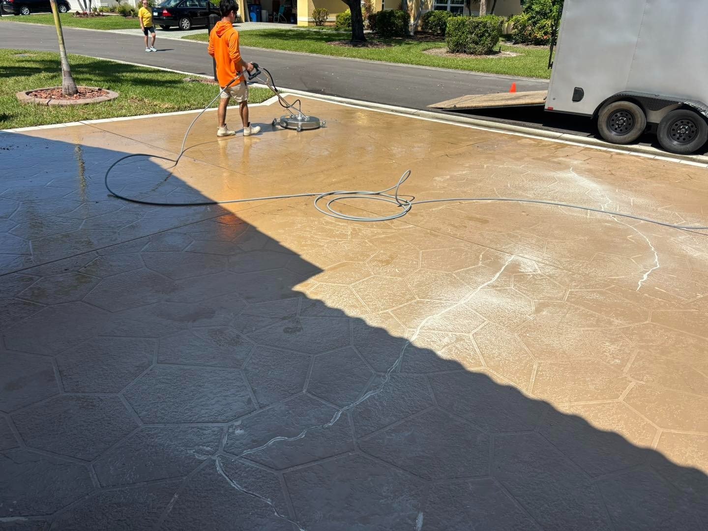 Worker using equipment on a wet brown patterned driveway