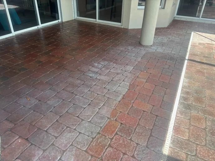 Red and brown paver patio beside sliding doors and a round column