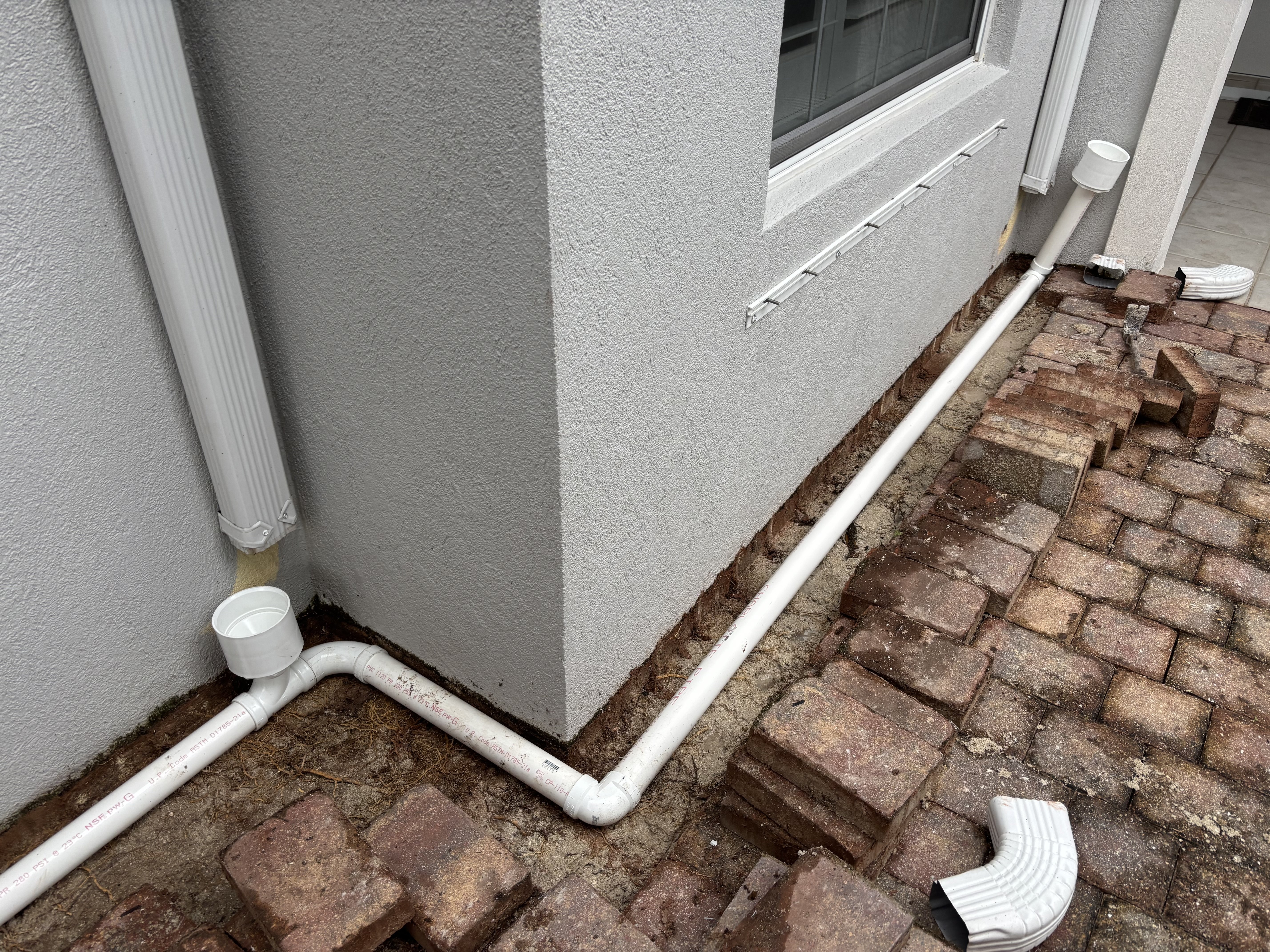 Outdoor drainage and water-management work beside a paved surface