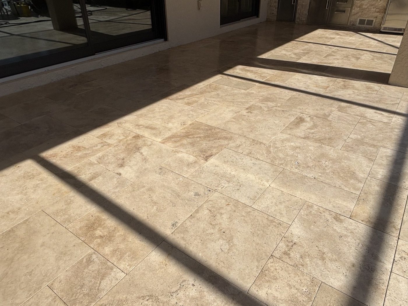 Travertine paving in sun and shade beside the pool enclosure in Estero