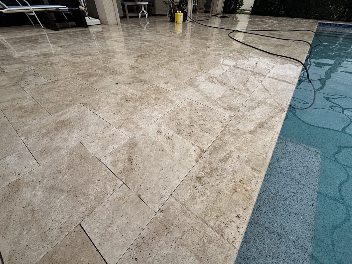 Light travertine pool deck beside the pool at an Estero home