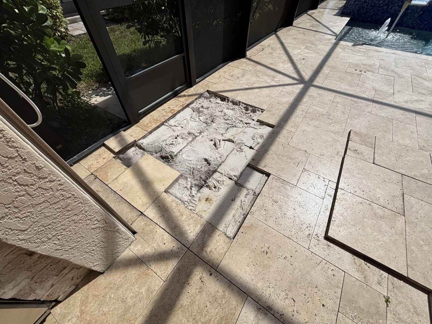 Travertine paving lifted for repairs beside the pool enclosure in Estero