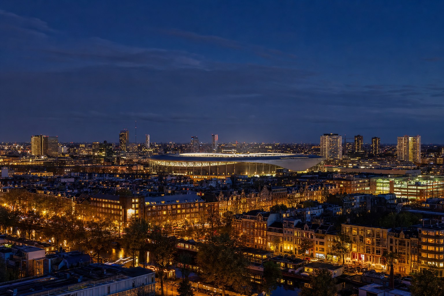 A European city and illuminated football stadium at dusk