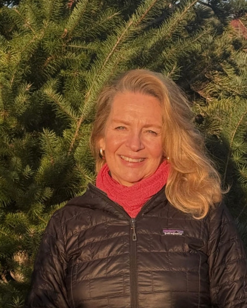 Diana Kelly Morse standing in front of evergreen trees