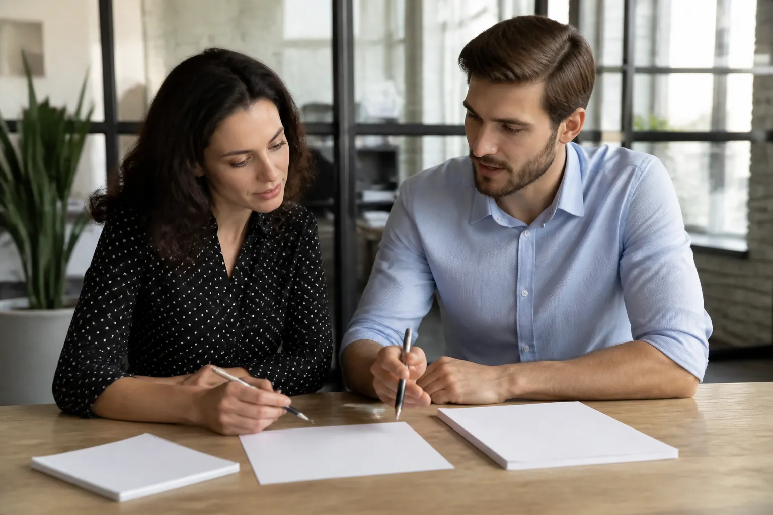 Two colleagues collaborating with blank notes during a business meeting