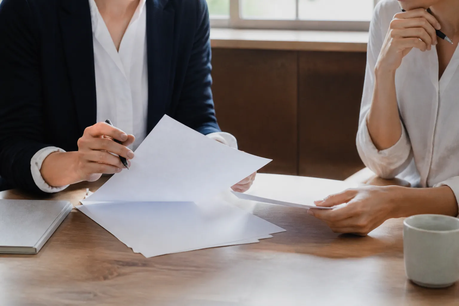 Two colleagues reviewing blank documents during a professional meeting