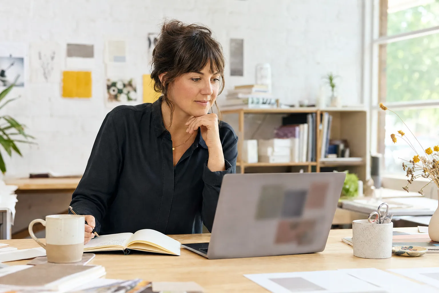 Small business owner reviewing website details on a laptop at a studio desk