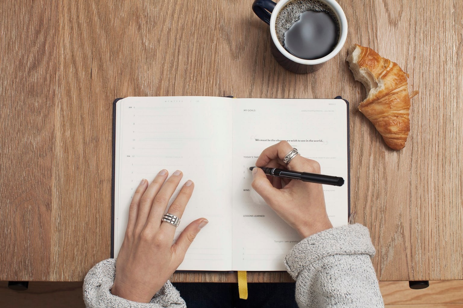 Open planner on a desk beside coffee and a pen