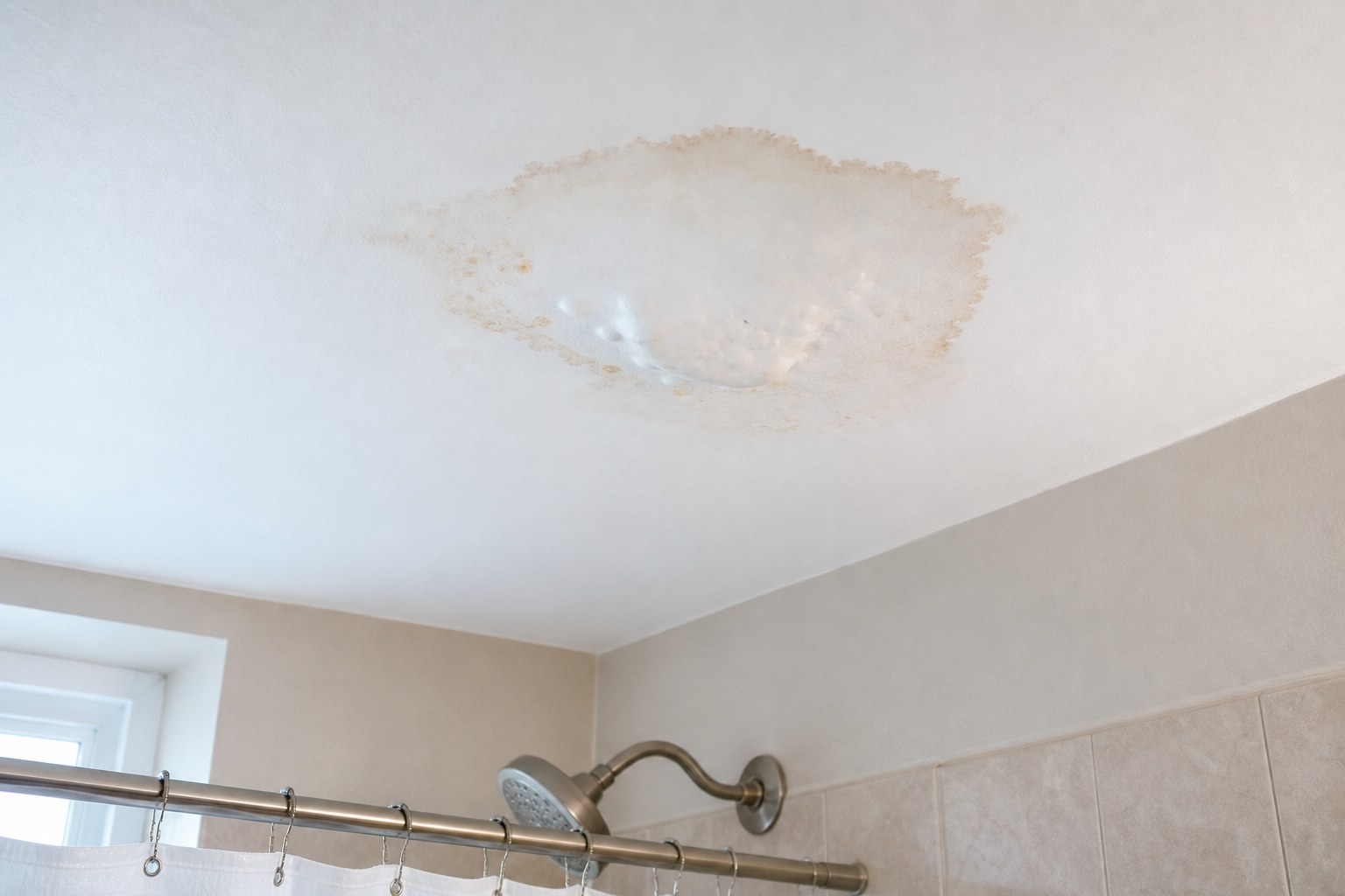 Water stain and bubbling paint on a bathroom drywall ceiling