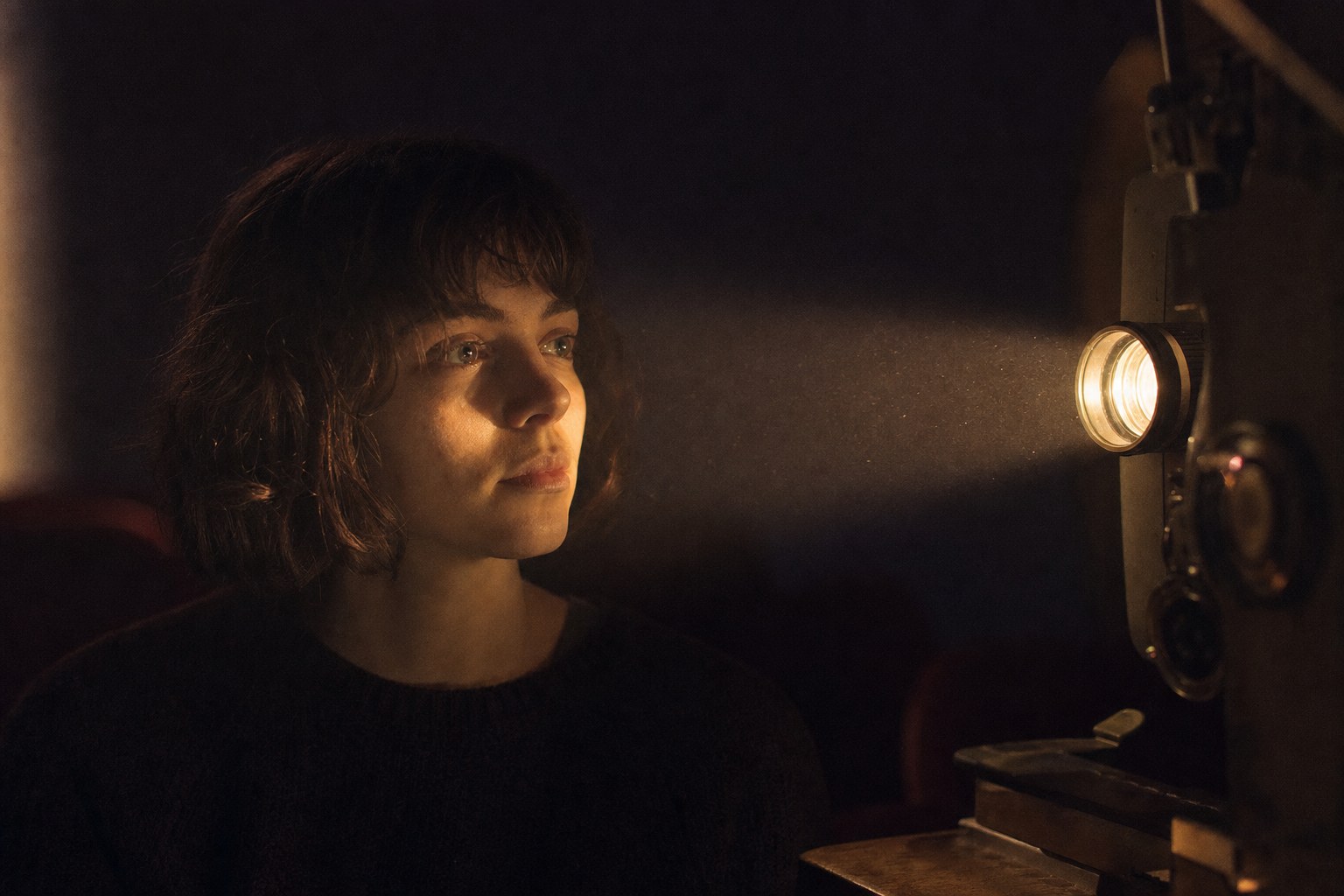 A face softly illuminated by a film projector