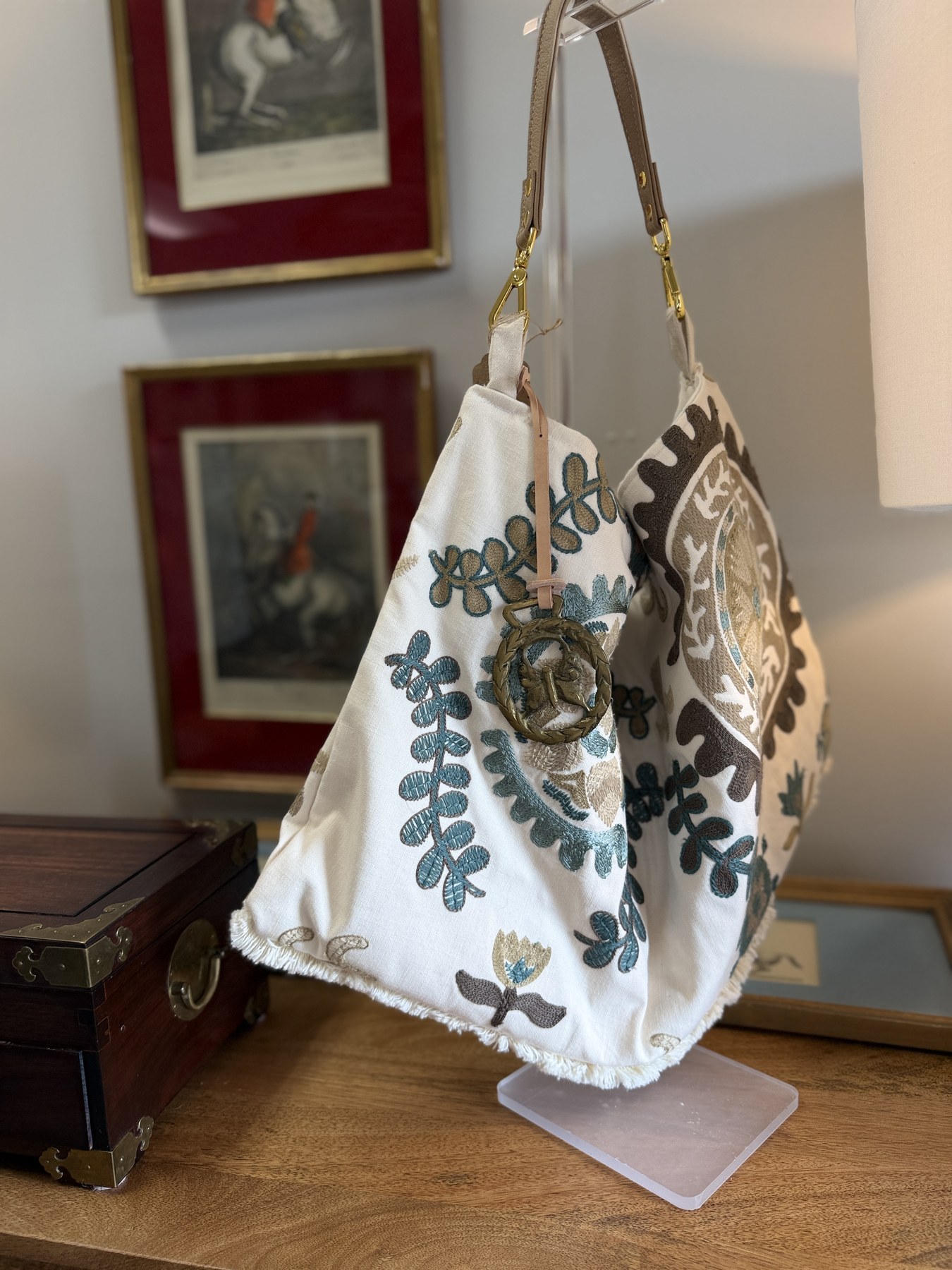 Embroidered sporting tote beside vintage framed art and a train case