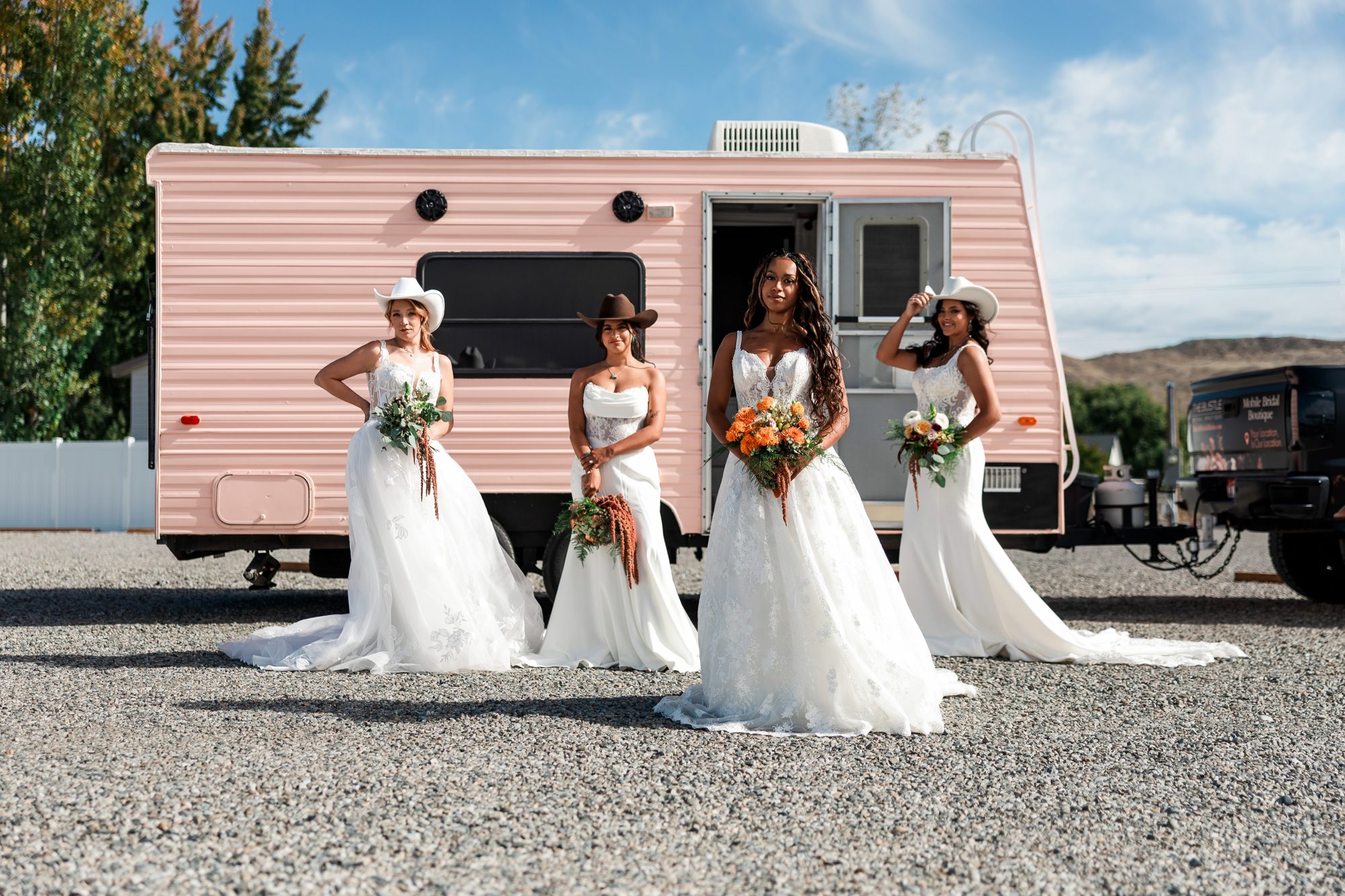Four bridal looks in front of The Bustle’s pink mobile bridal suite