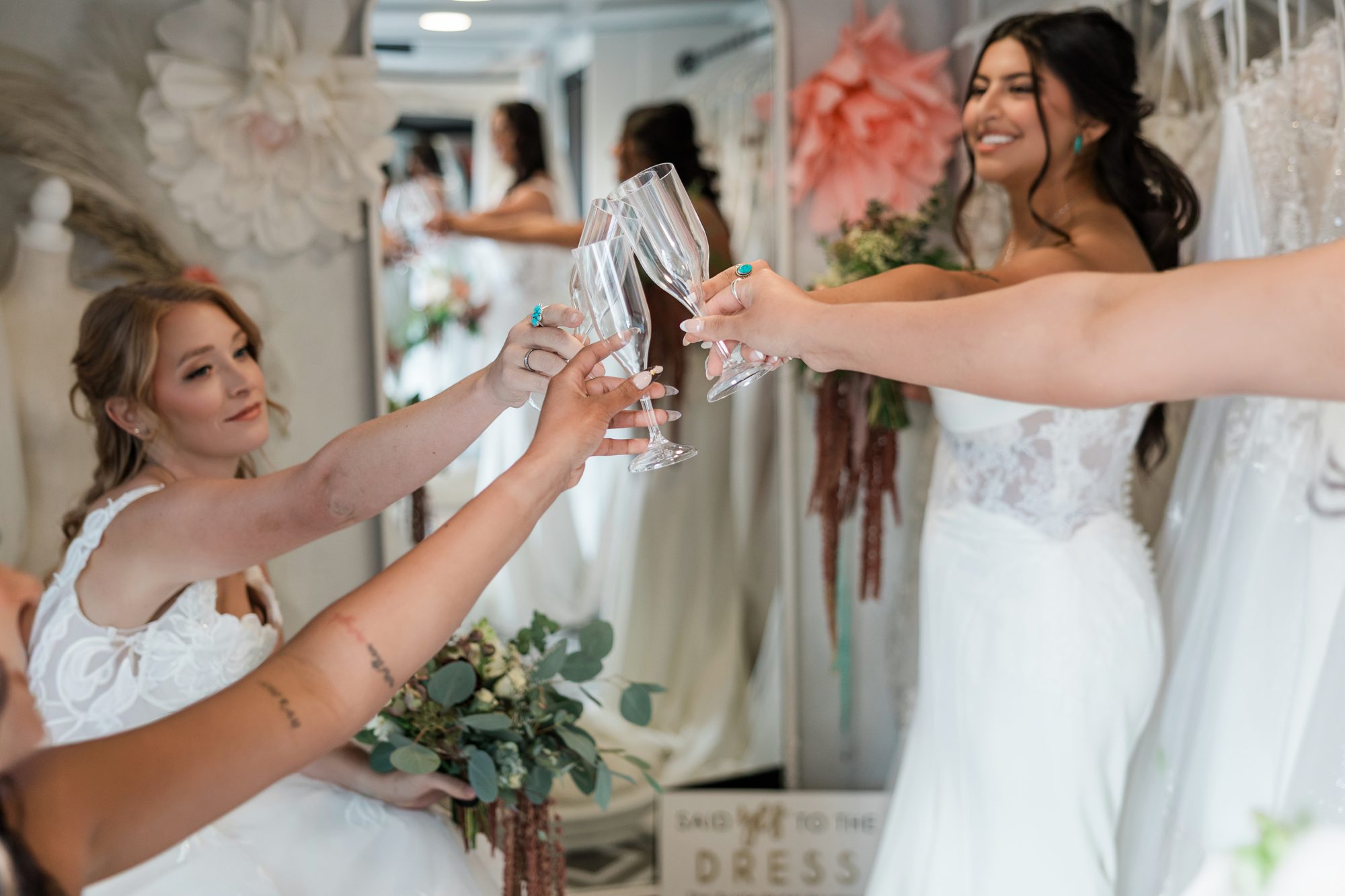Brides raising champagne glasses together inside The Bustle mobile bridal suite