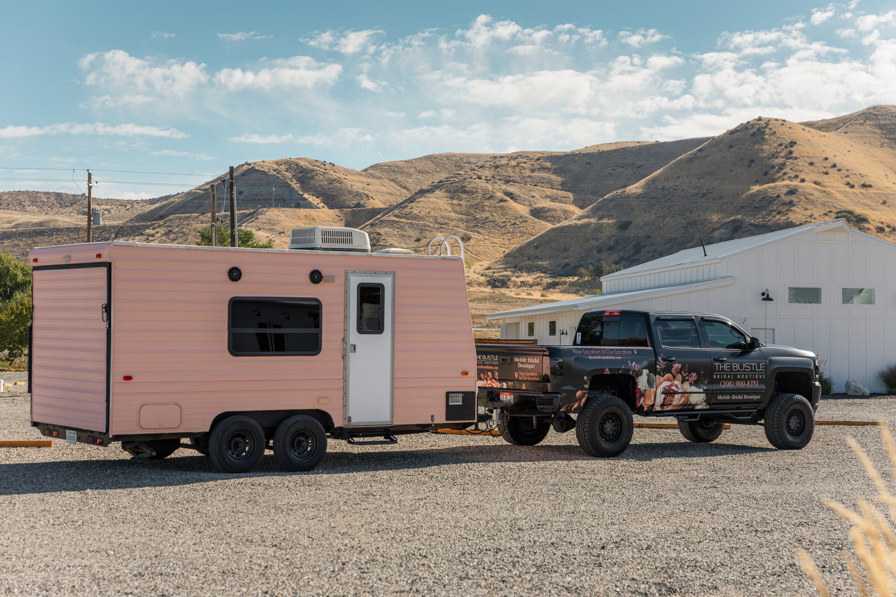 The pink Bustle mobile bridal suite and branded truck parked beneath Idaho hills