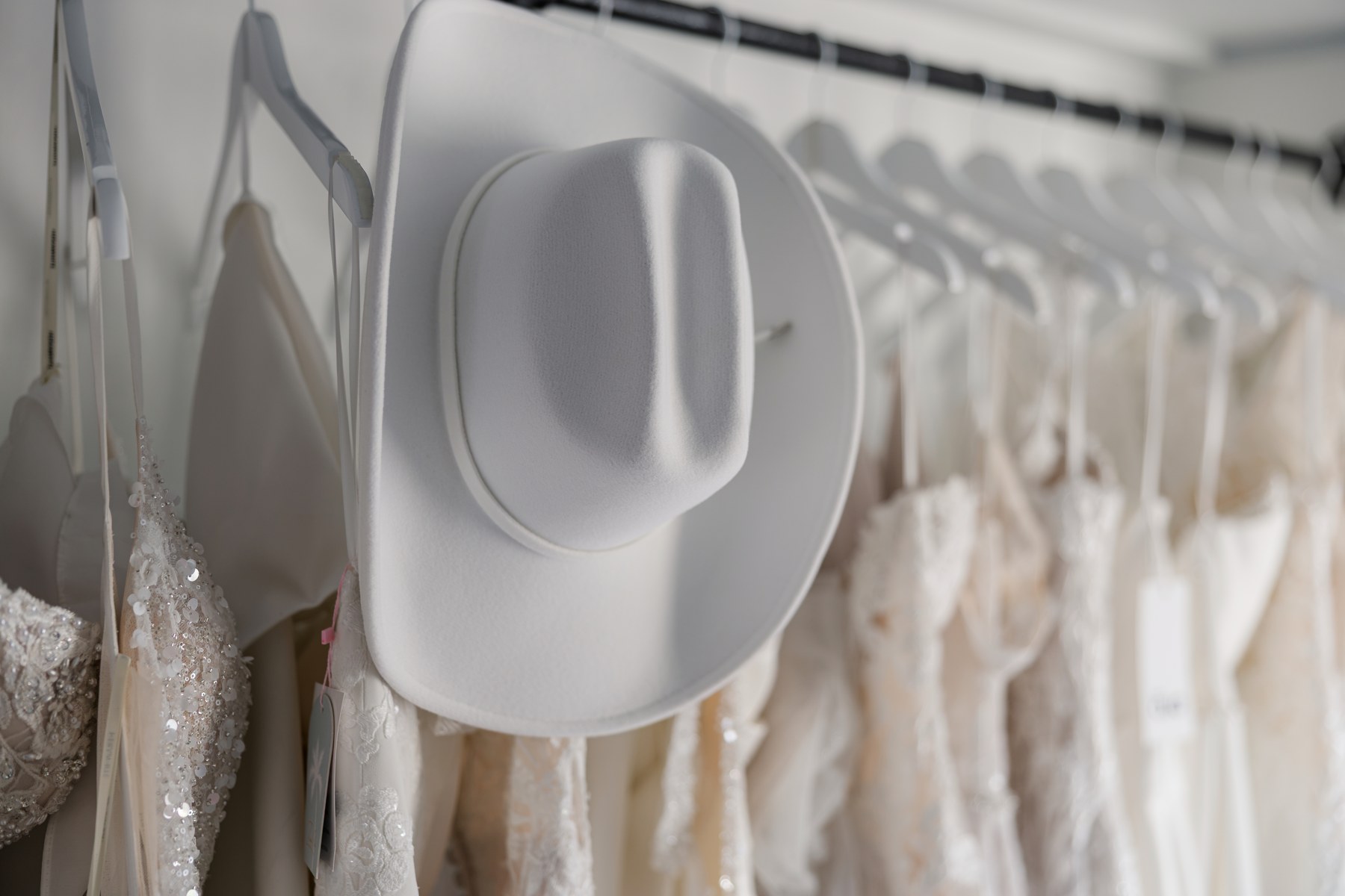 Wedding gowns and a white hat on the in-home bridal studio gown rail