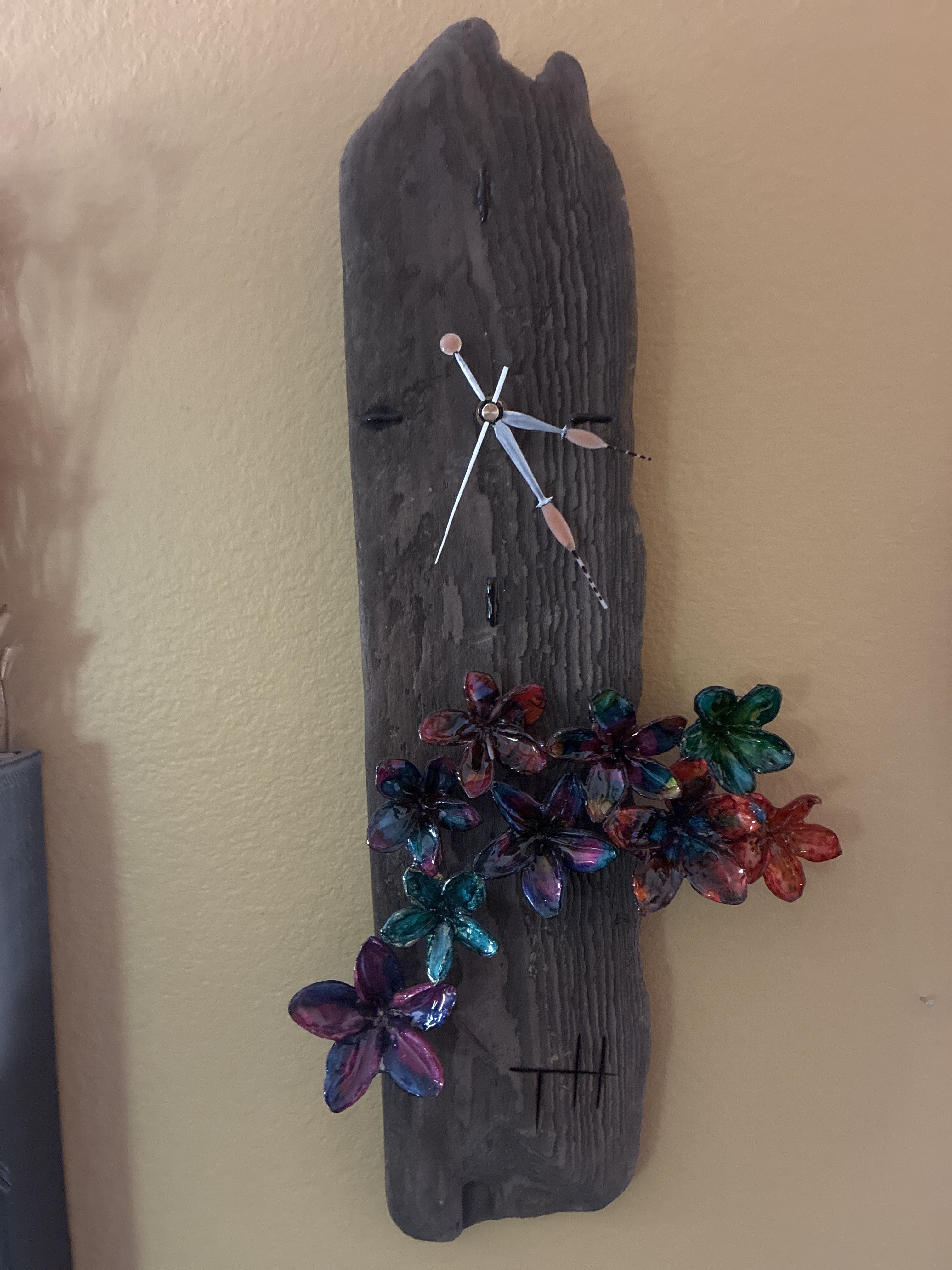 Handmade dark wood wall art with colorful preserved flower forms and a dragonfly