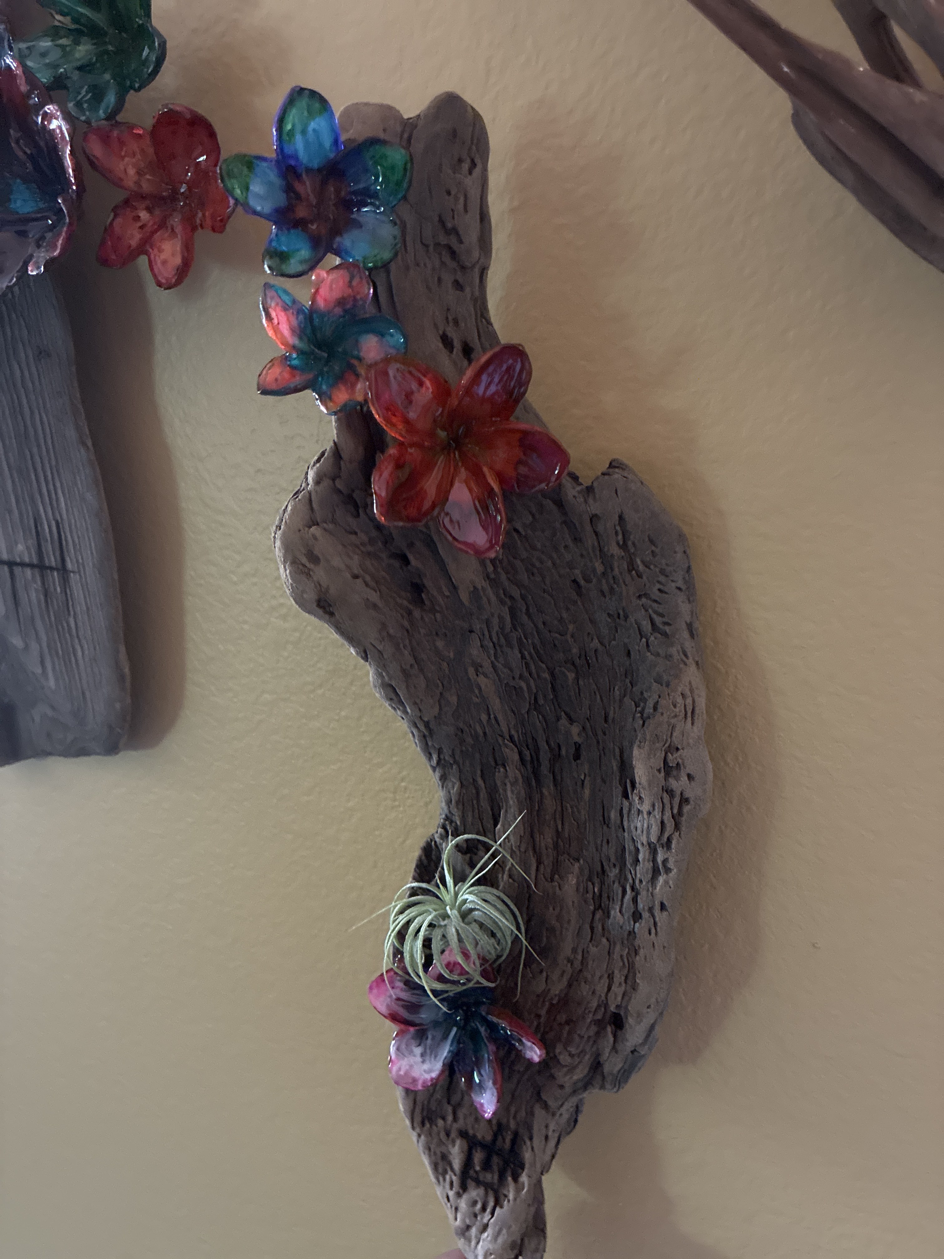 Close-up of handmade wood wall art with colorful resin flower forms