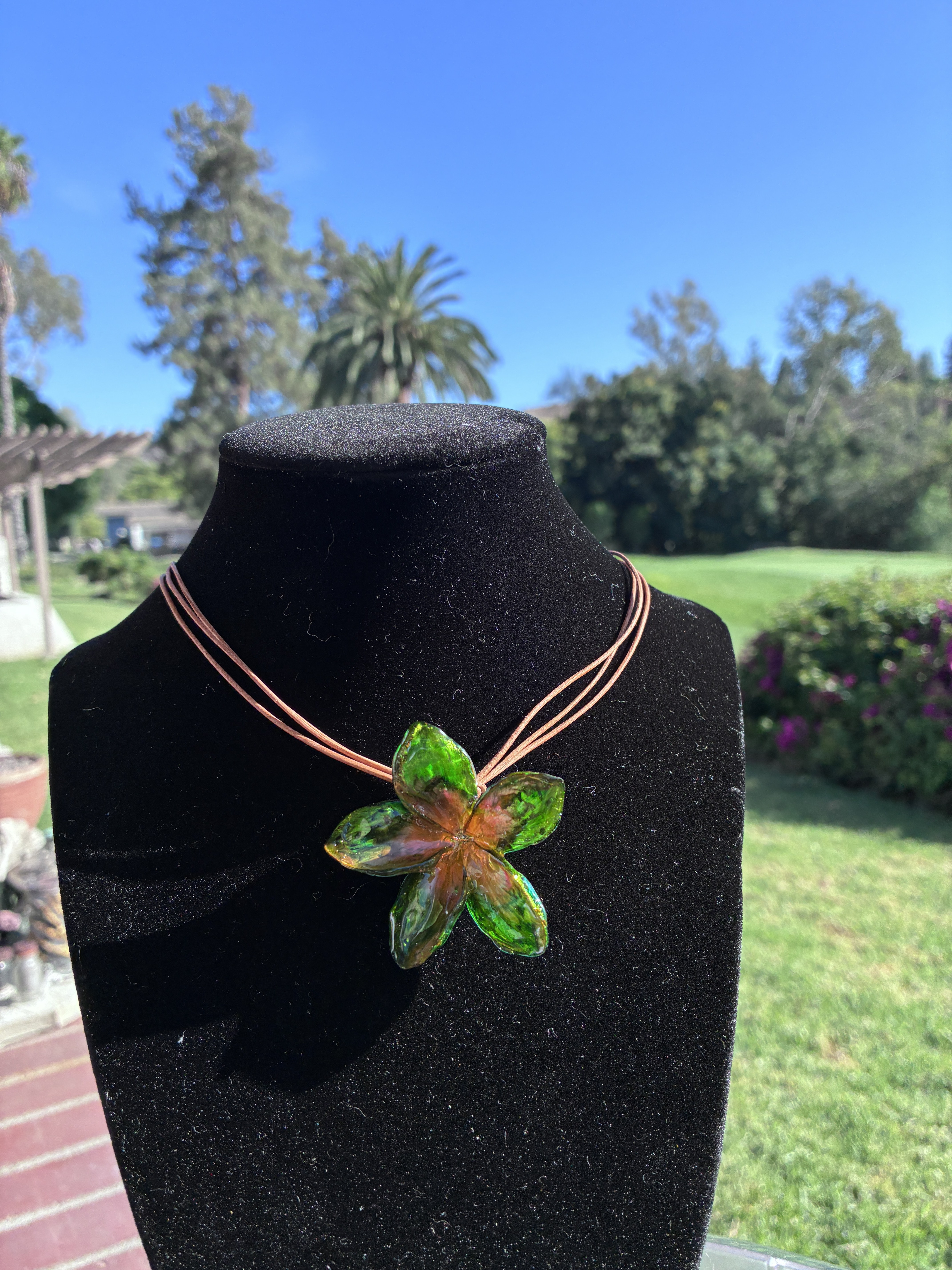 Green floral handmade necklace displayed on a black jewelry bust