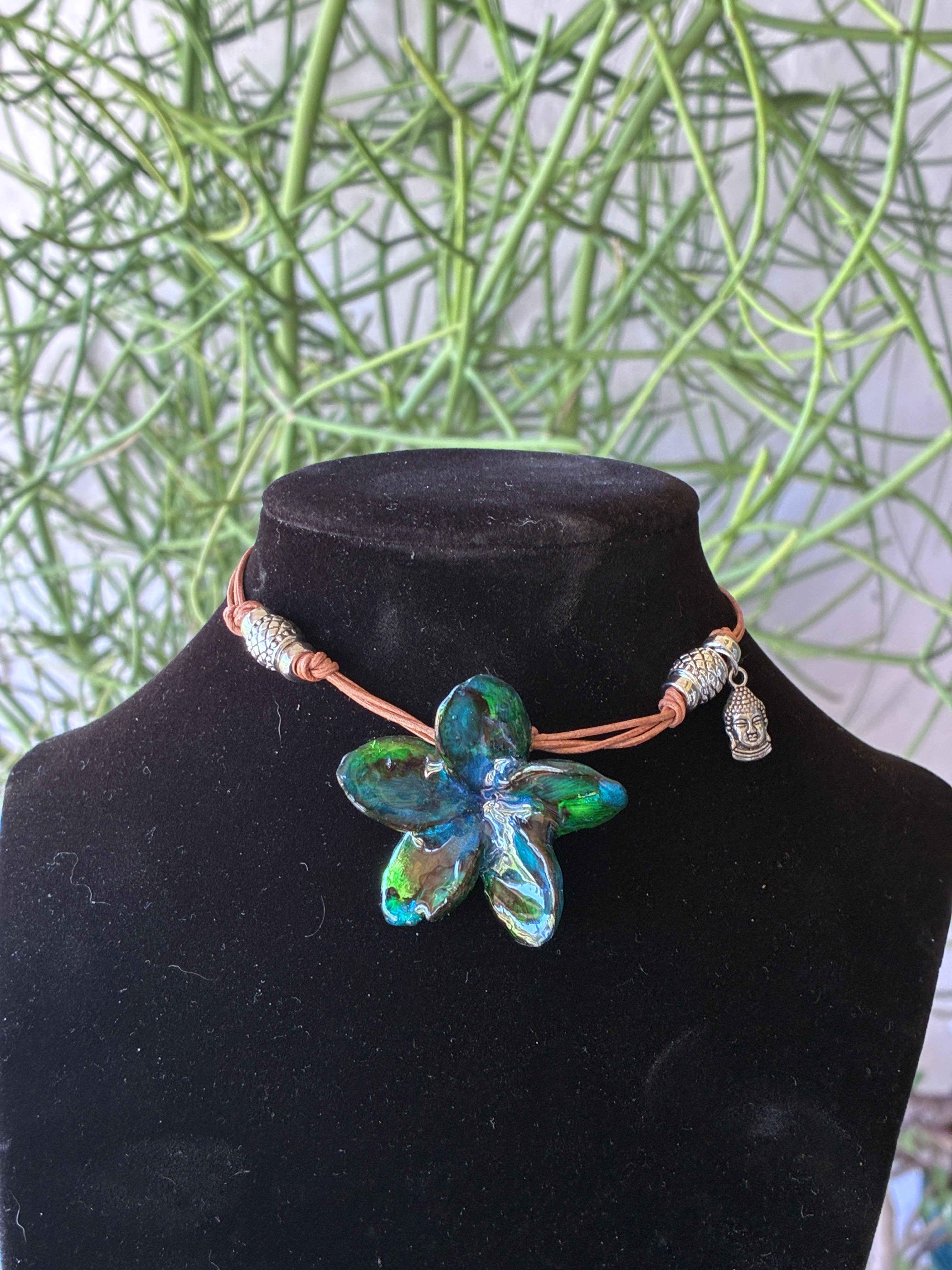 Teal and green floral handmade necklace displayed on a black jewelry bust