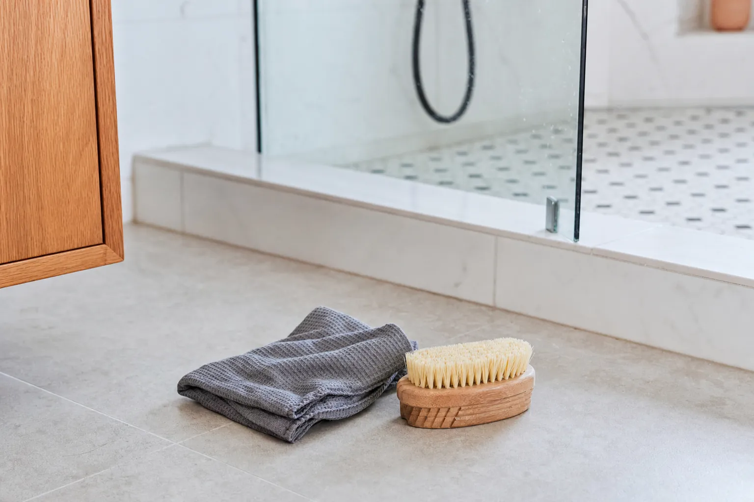 Bathroom floor, shower threshold, cleaning cloth, and scrub brush