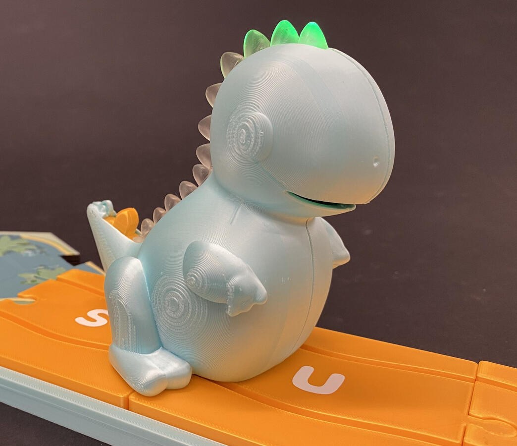 Close view of Dash the Dino on the orange alphabet path