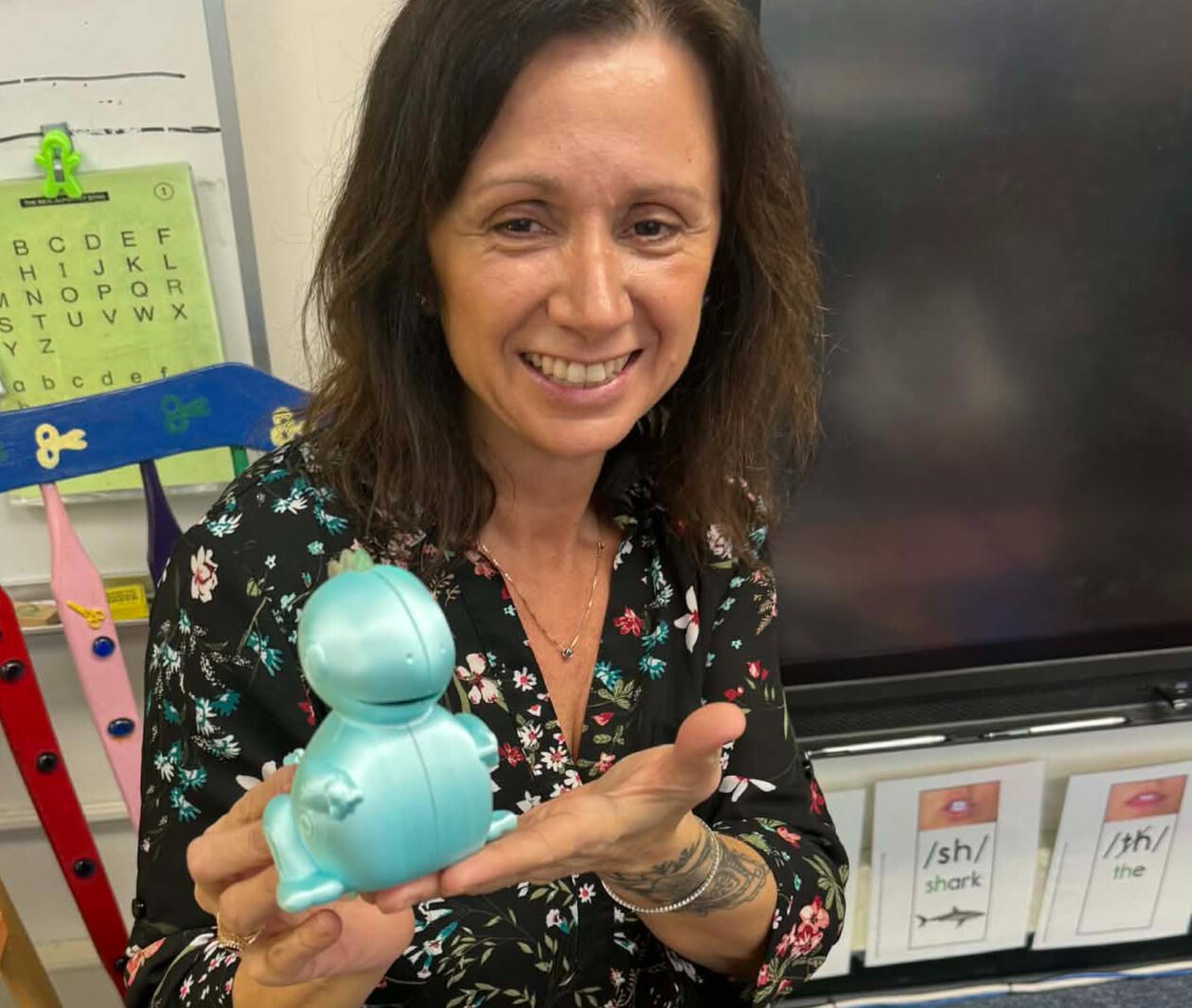 Angela Martinez holding Dash the Dino in a classroom