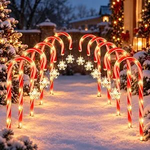 Red and white candy cane pathway lights with illuminated snowflake accents lining a snowy walkway