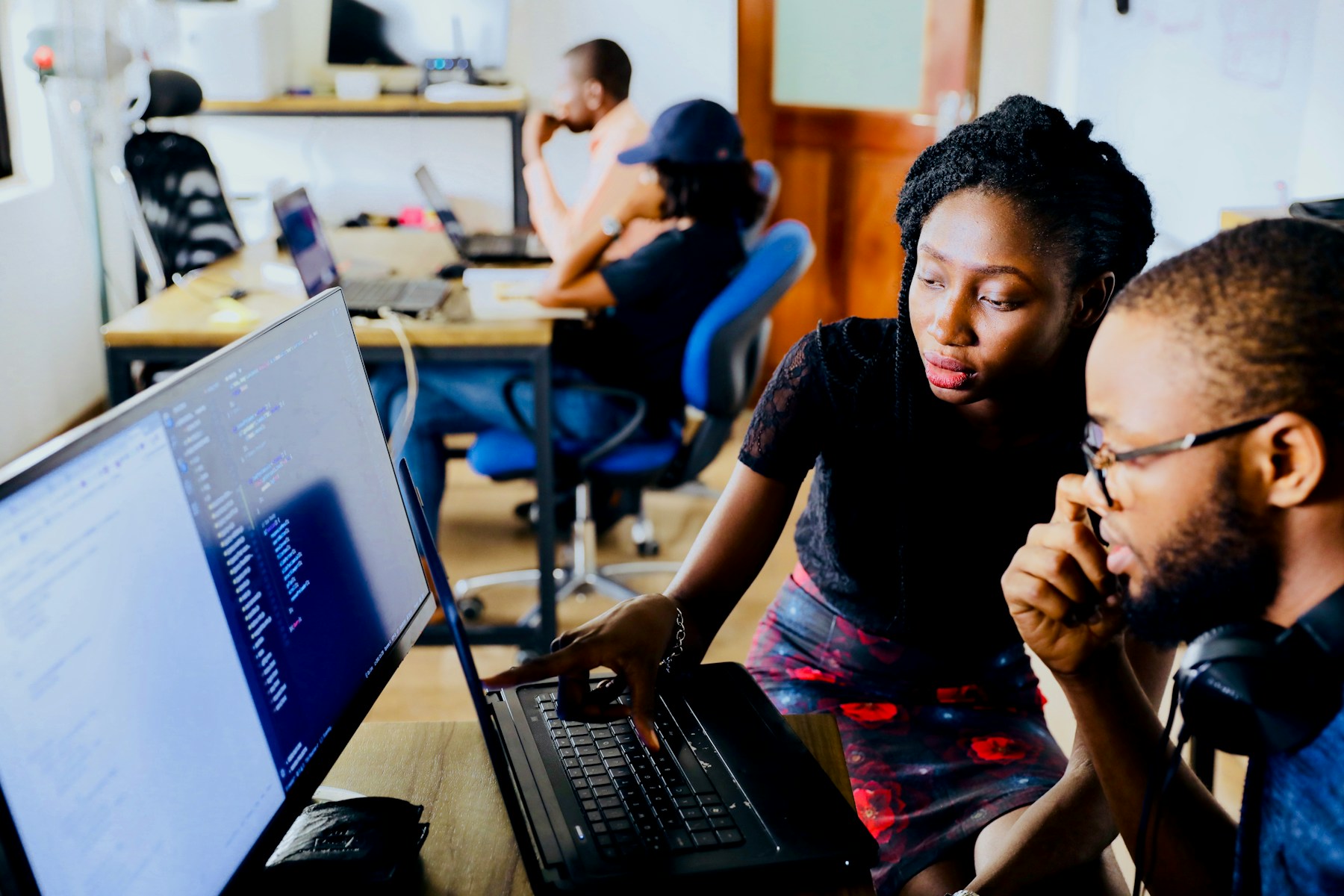 Two colleagues working together at a laptop in a shared office