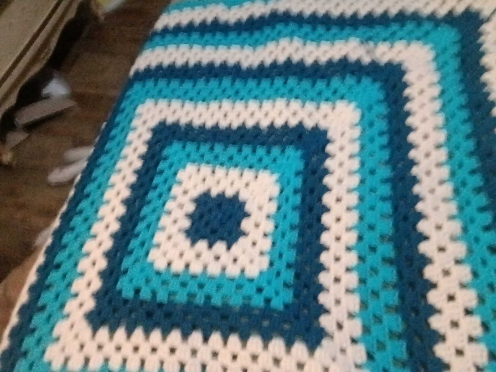 Infinity Granny Square Baby Blanket with turquoise, deep blue, and cream crochet stripes