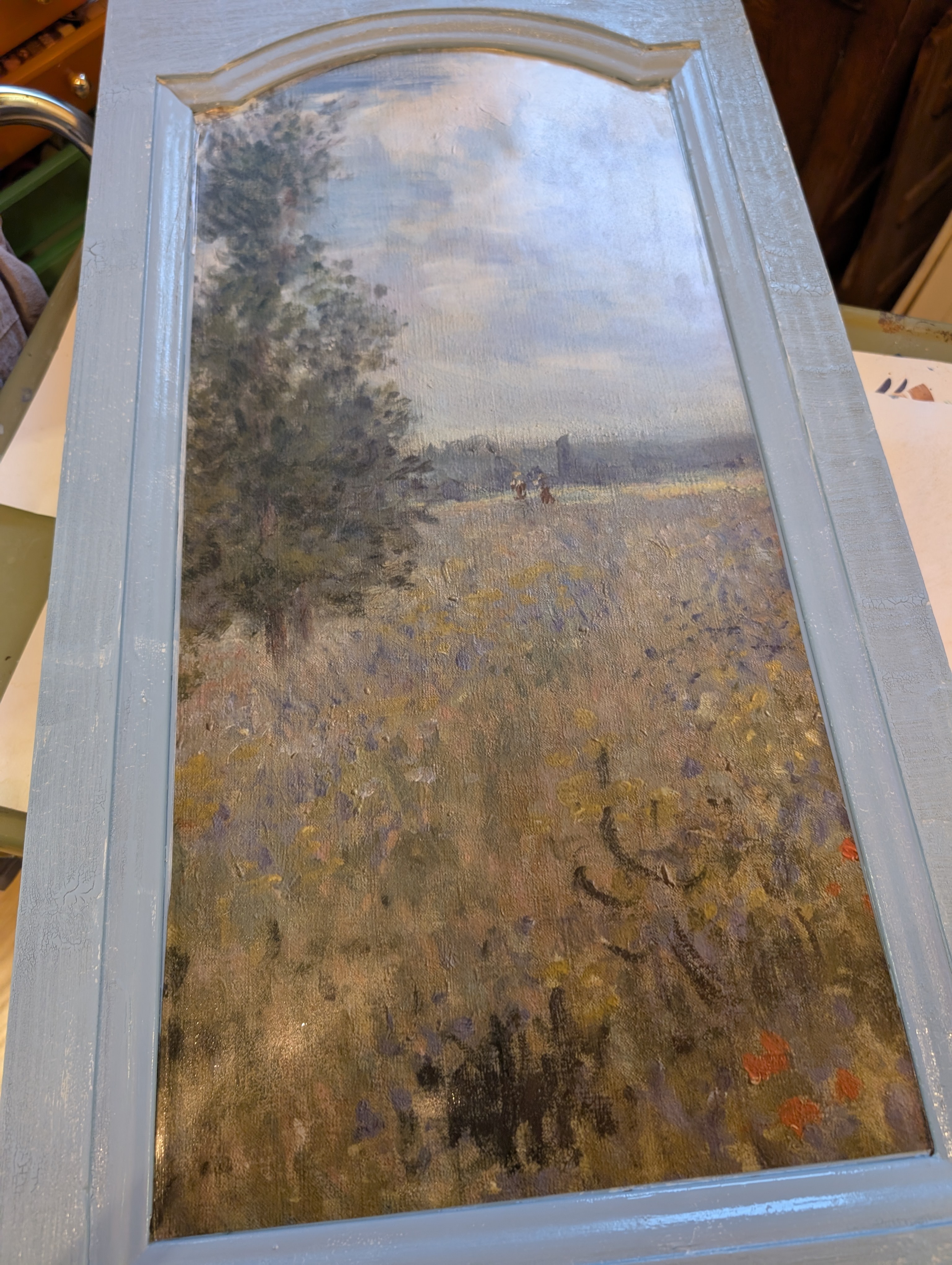 Landscape decoupage placed within a painted cabinet-door frame before the finish is complete