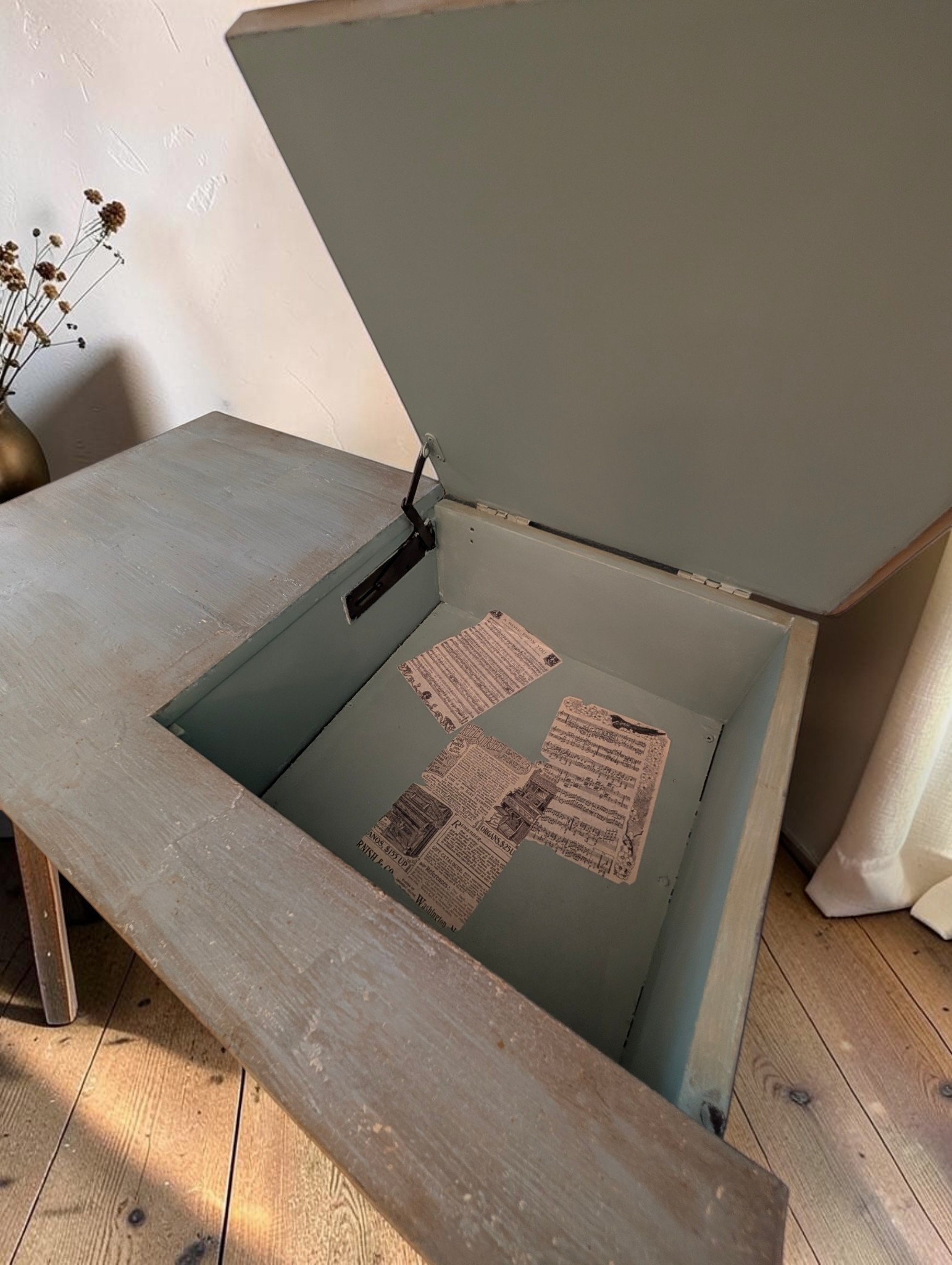 Green storage bench with newspaper decoupage inside the base