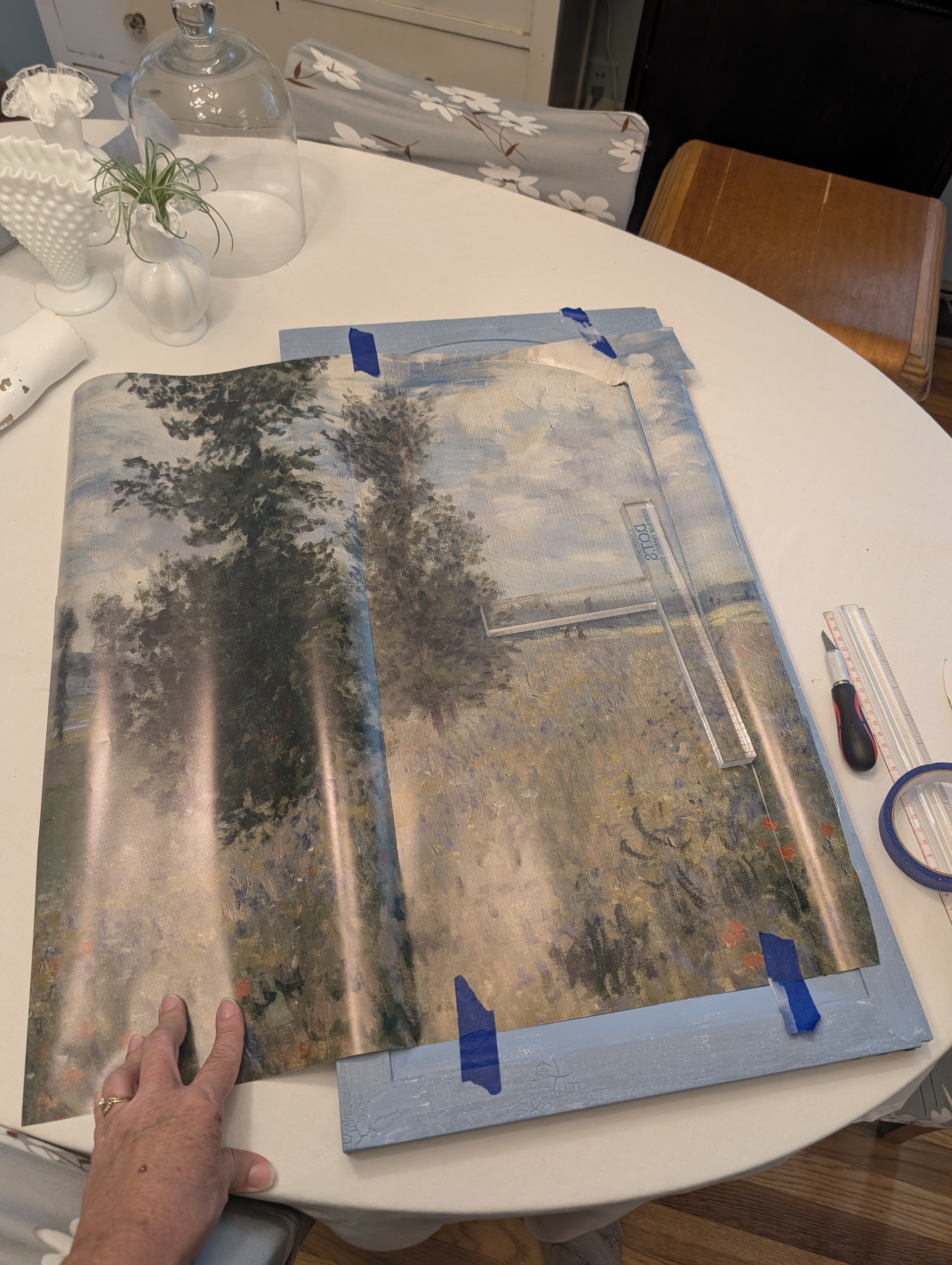 Testing the placement of a landscape paper before cutting it for a cabinet door