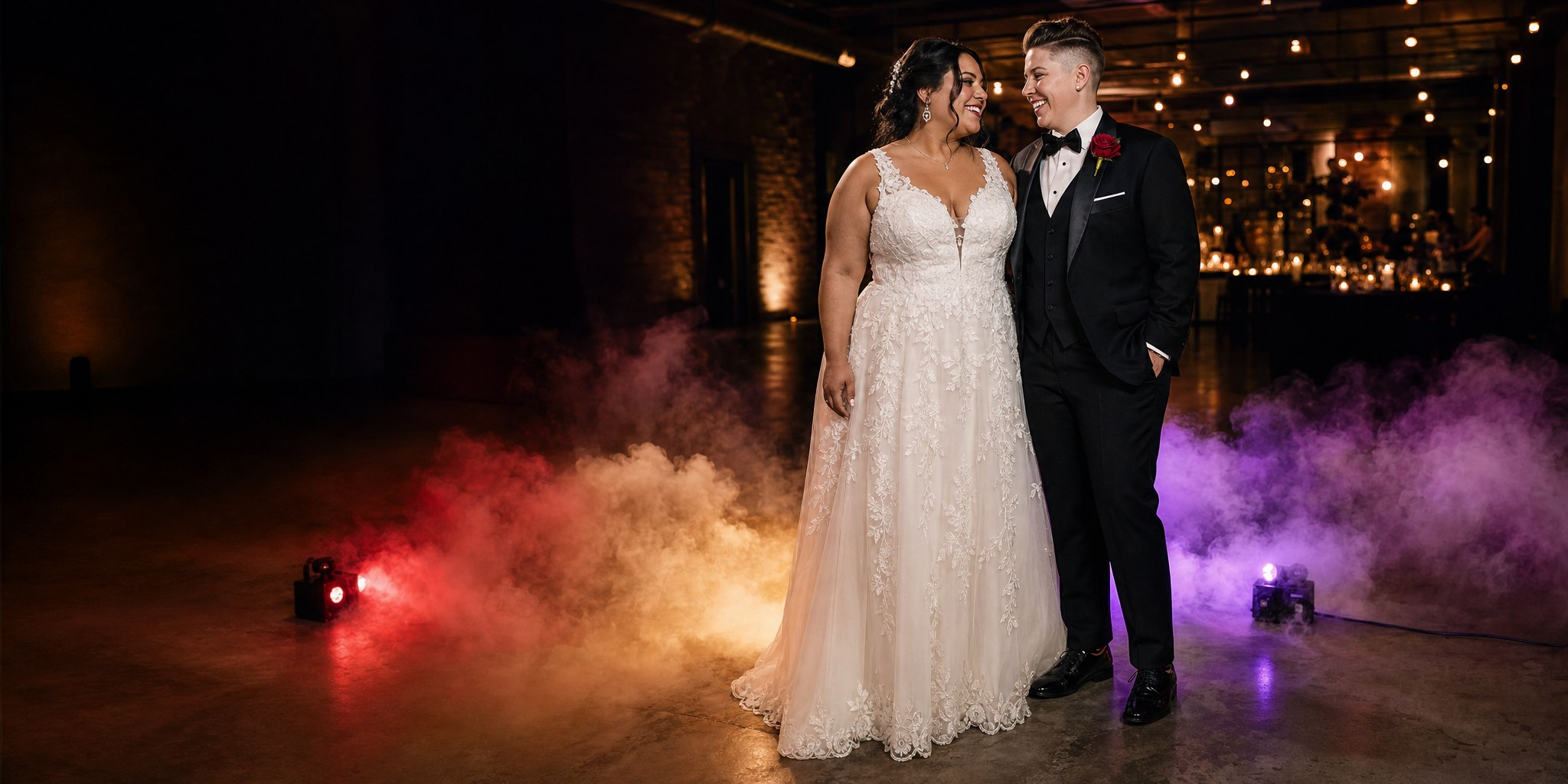Two brides celebrating at a wedding reception with colorful low fog