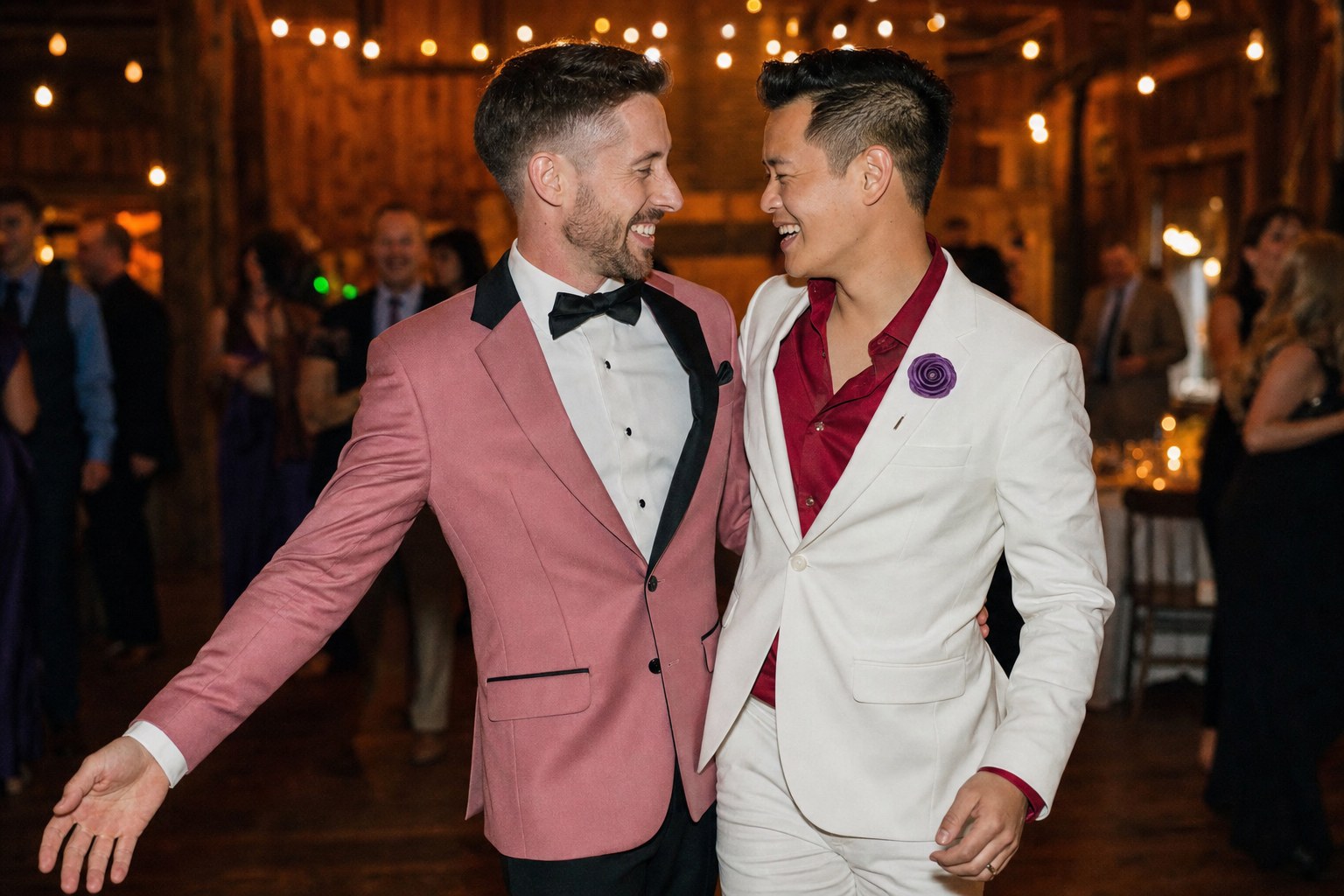 Two grooms laughing together at a wedding reception